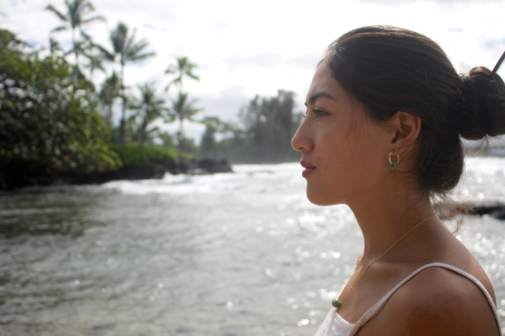 Woman standing by a body of water with trees in the background